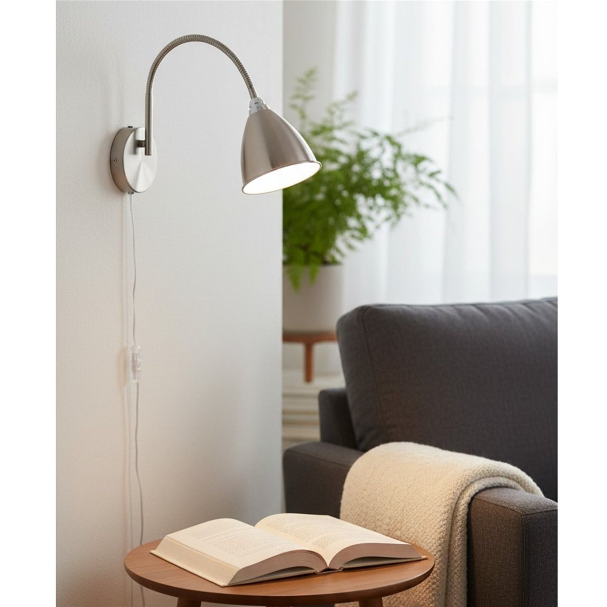 Aldon Swan Neck Plug-In Wall Light in brushed steel mounted beside an armchair and side table in a living room