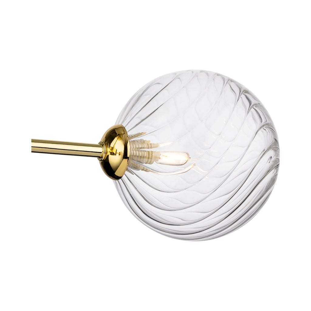 Close-up of the swirled clear glass globe and brass arm on the Ashby Semi-Flush Ceiling Light
