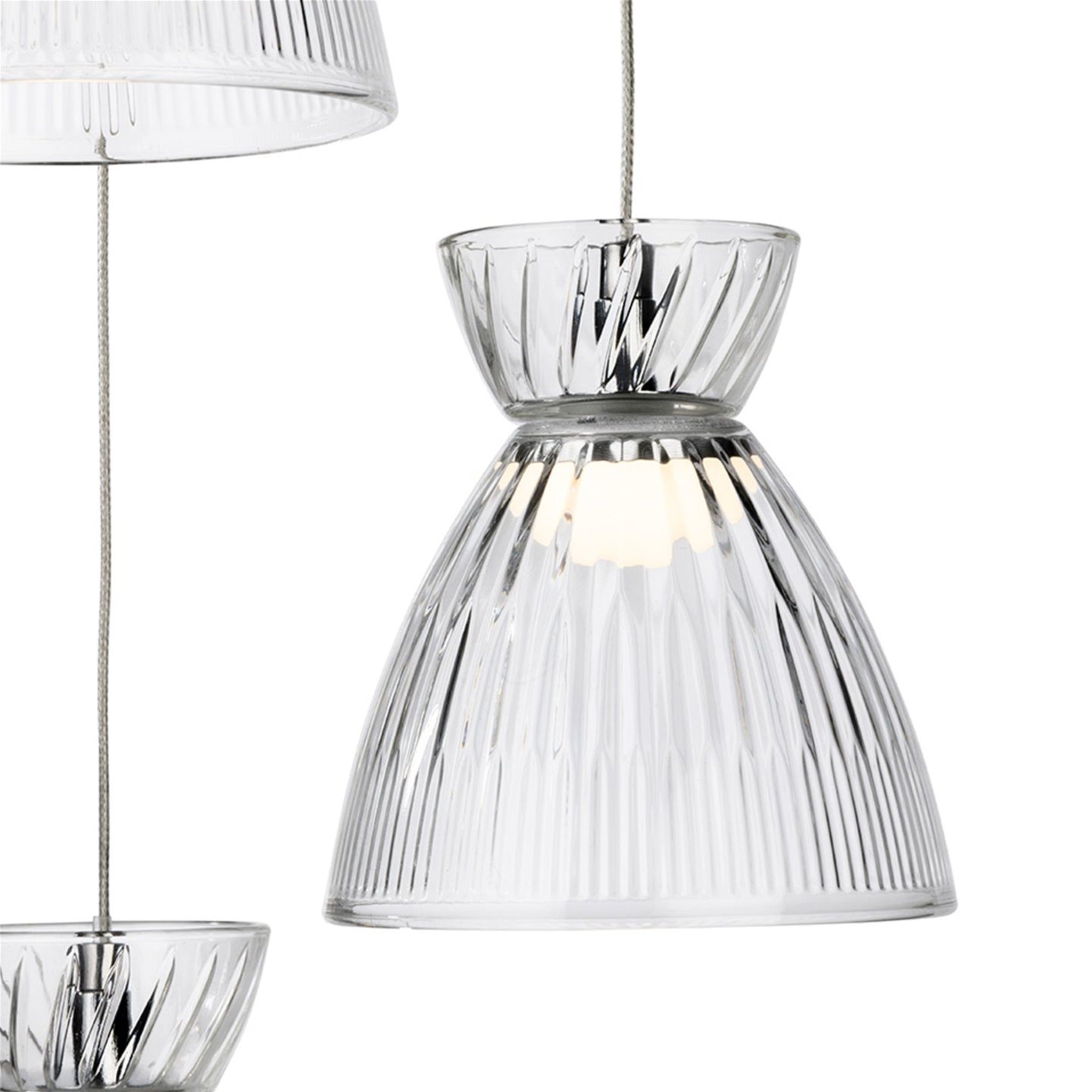 Clear fluted glass shade of the Bexley 3 Light Cluster Pendant, lit, with the chrome rose above