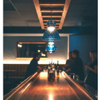 Bexley pendant in blue glass lit above a bar