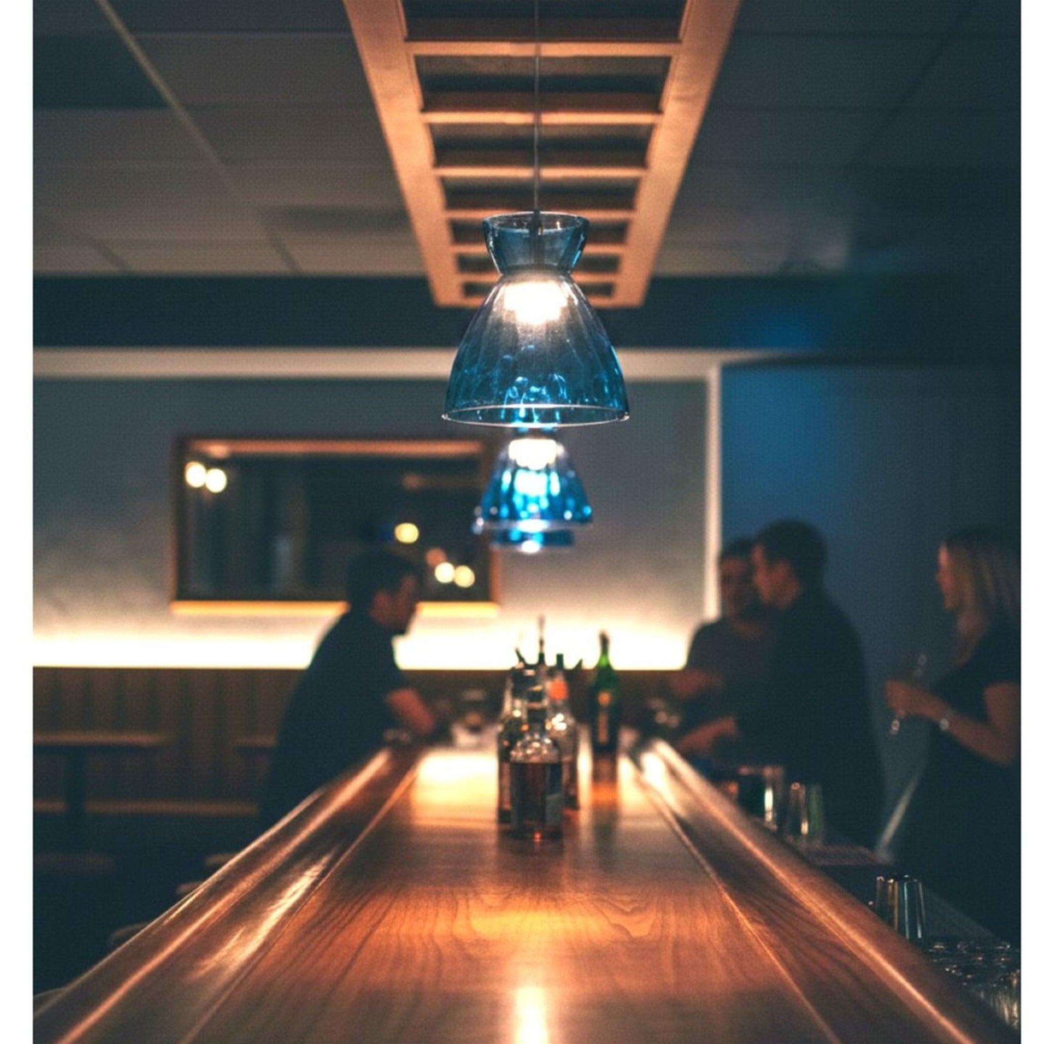 Bexley pendant in blue glass lit above a bar