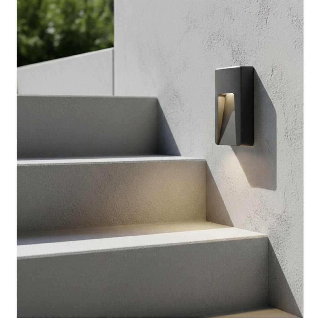 Brecon Oblong LED Wall & Step Light in graphite mounted on a rendered wall beside outdoor steps