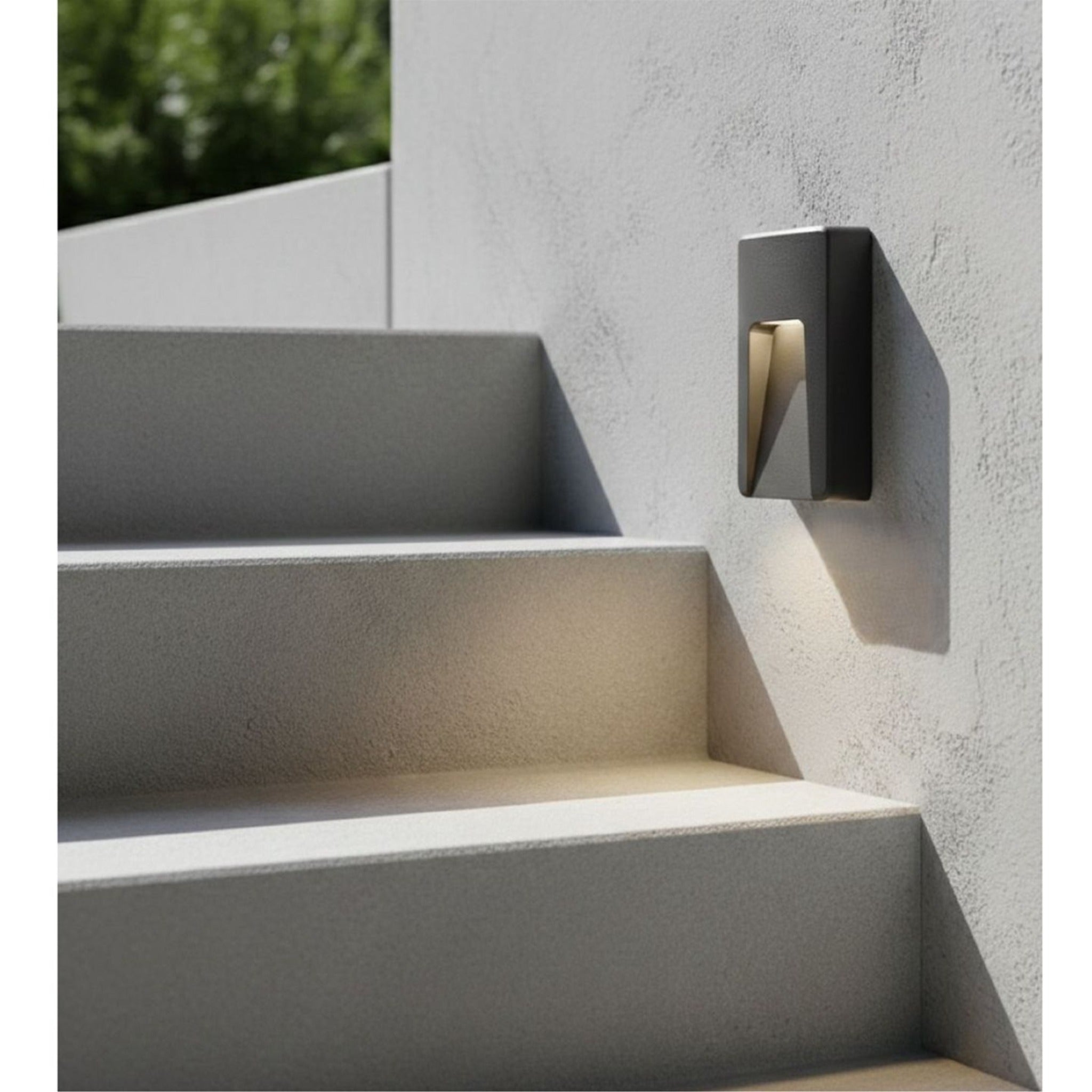 Brecon Oblong LED Wall & Step Light in graphite mounted on a rendered wall beside outdoor steps