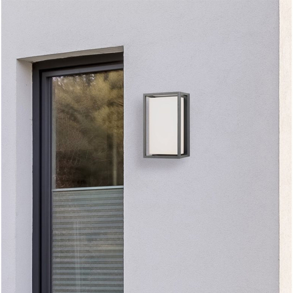 Elgin Framed Panel LED Outdoor Wall Light in graphite mounted on a rendered wall beside a front door in daylight
