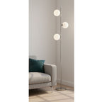 Ellis Triple Globe Floor Lamp in brushed steel standing in a living room corner beside a sofa