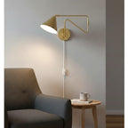 Fenwick Swing Arm Plug-In Wall Light in brushed brass, lit above an armchair and side table
