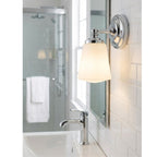 Hadley Opal Glass Bathroom Wall Light in chrome, lit beside a mirror above a bathroom basin
