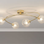 Linden Swirled Glass 4 Light Flush Ceiling Light in brass, lit on a living room ceiling