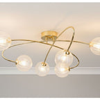 Linden Swirled Glass 6 Light Flush Ceiling Light in brass, lit on a ceiling