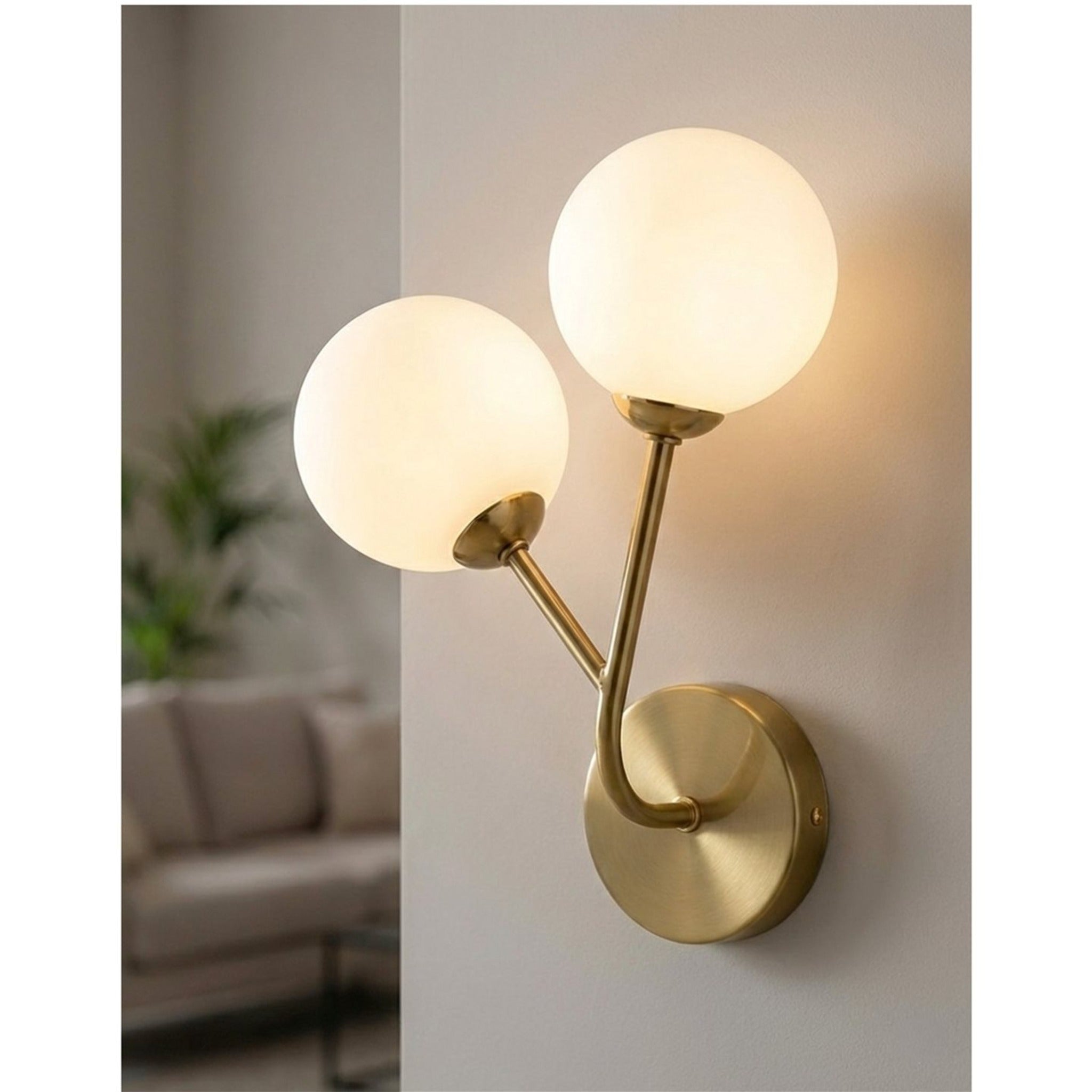 Lyra Twin Globe Wall Light in brushed brass lit on a living room wall