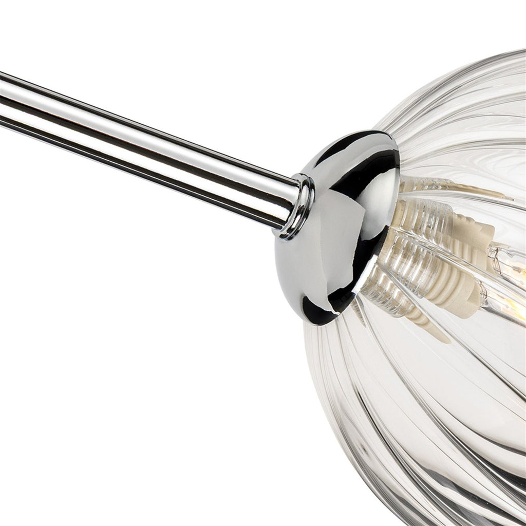 Close-up of a chrome arm meeting a clear ribbed glass globe