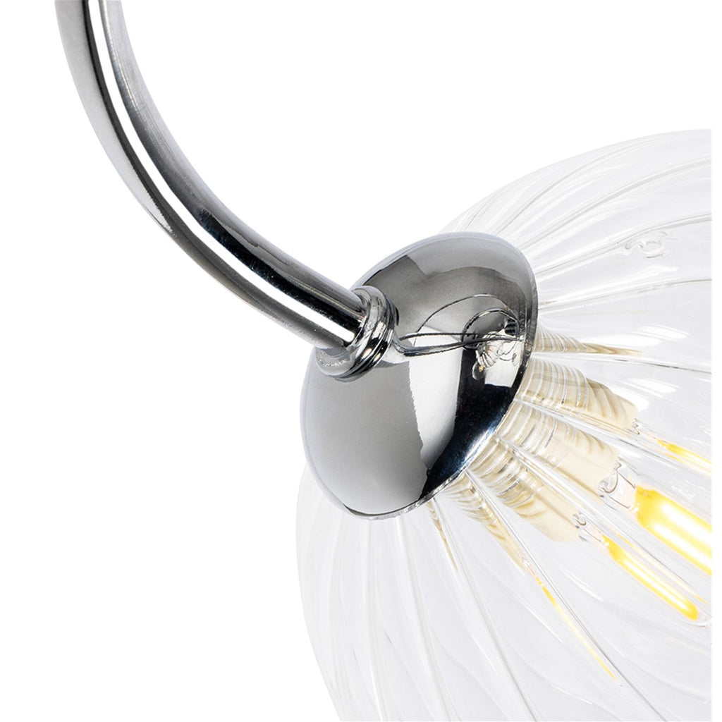 Close-up of a chrome arm meeting a clear ribbed glass globe