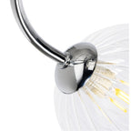 Close-up of a chrome arm meeting a clear ribbed glass globe