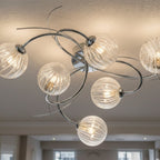Orla Swirl Globe 6 Light Flush Ceiling Light in chrome lit on a room ceiling