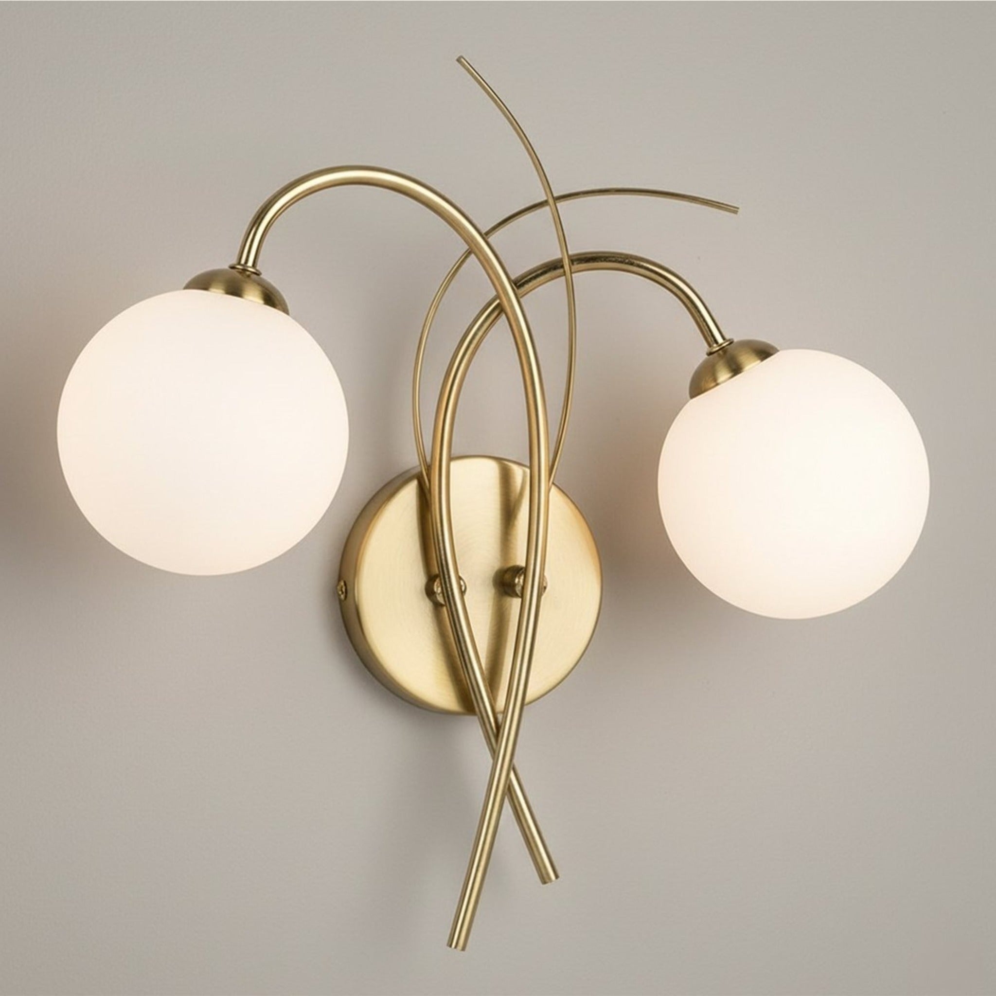 Orla Swirl Globe Wall Light in brushed brass mounted on a warm neutral wall