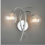 Orla Swirl Globe Wall Light in chrome lit against a grey wall