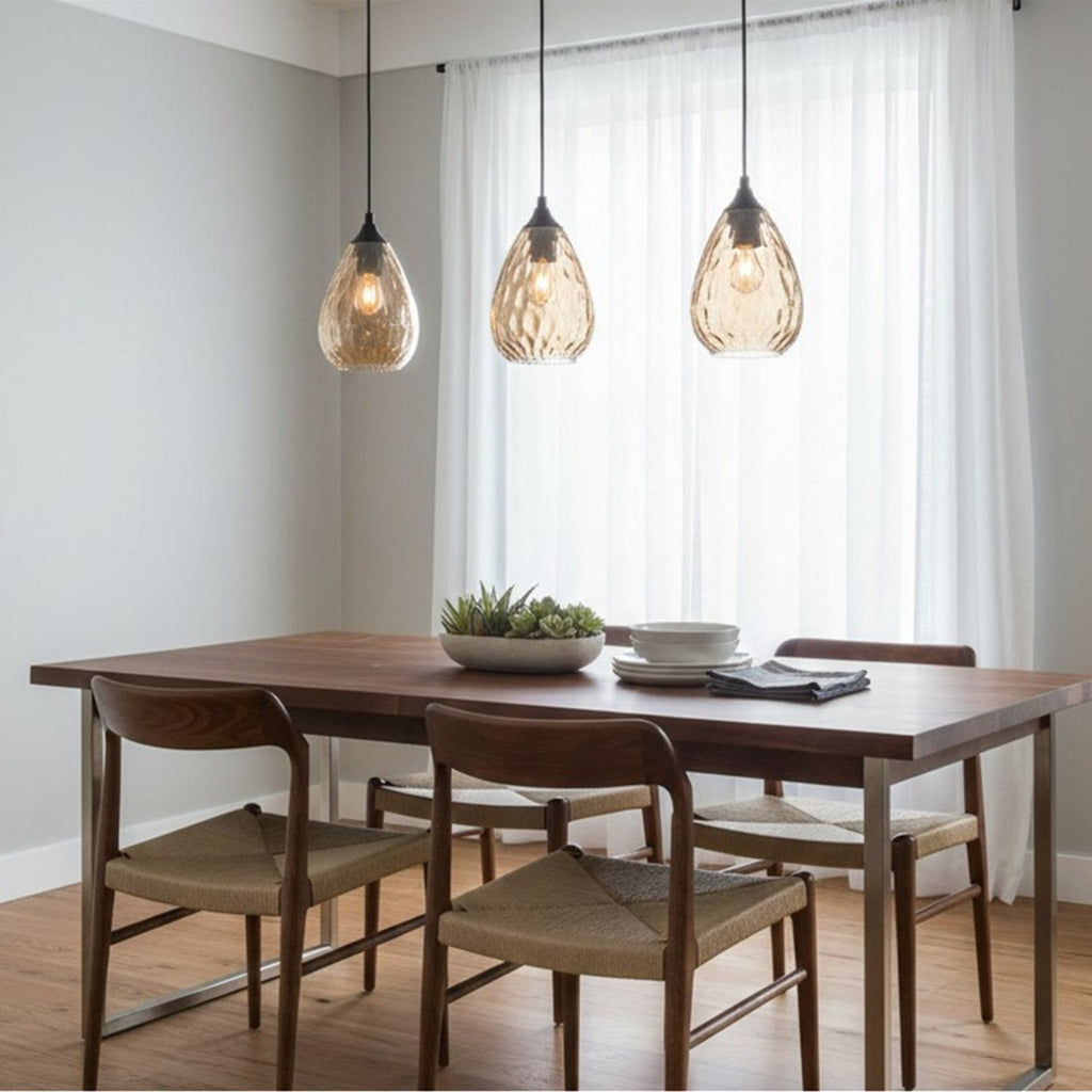 Three Orla Teardrop Glass Pendants in amber glass hanging in a row over a dining table
