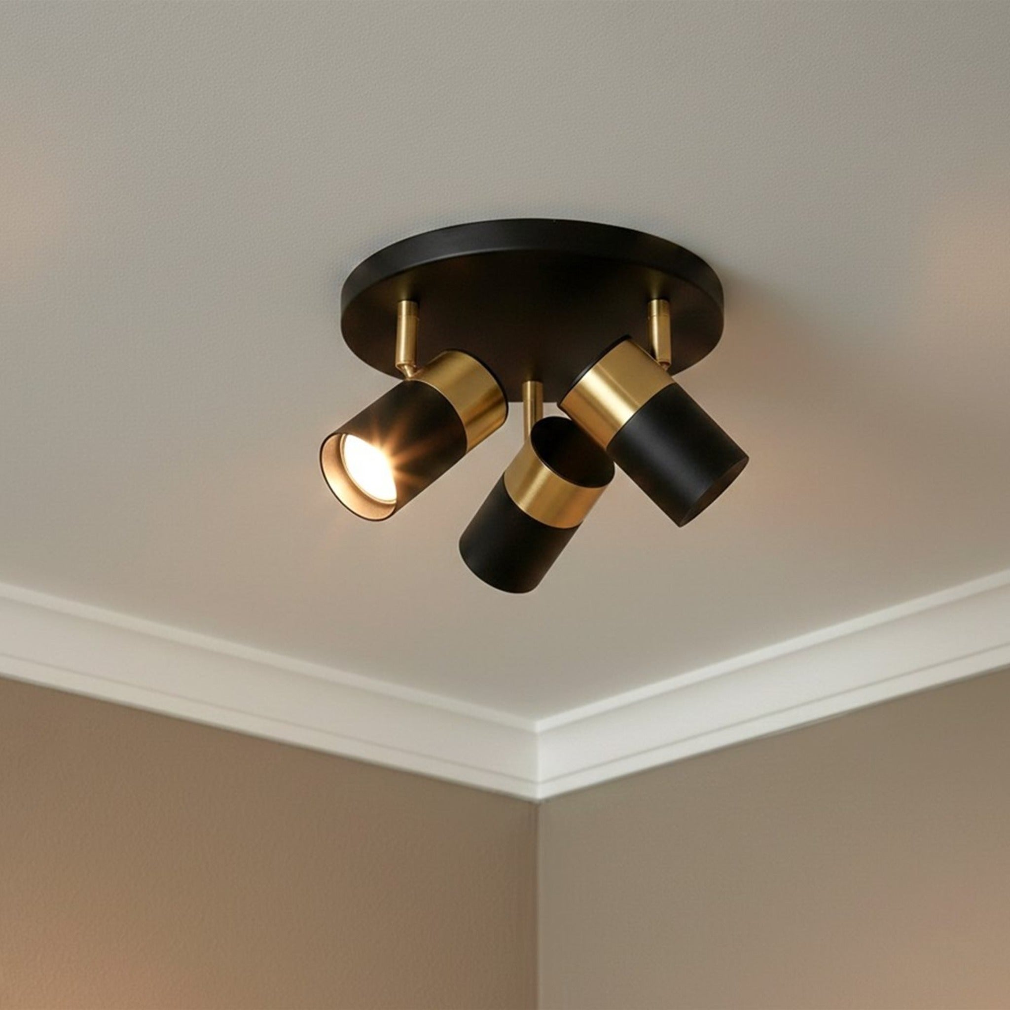 Renn 3 Light GU10 Flush Ceiling Spotlight in black with brushed brass fitted to a ceiling with the heads angled apart