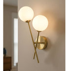 Ripley Glass Globe 2 Light Wall Light in brushed brass, lit on a hallway wall