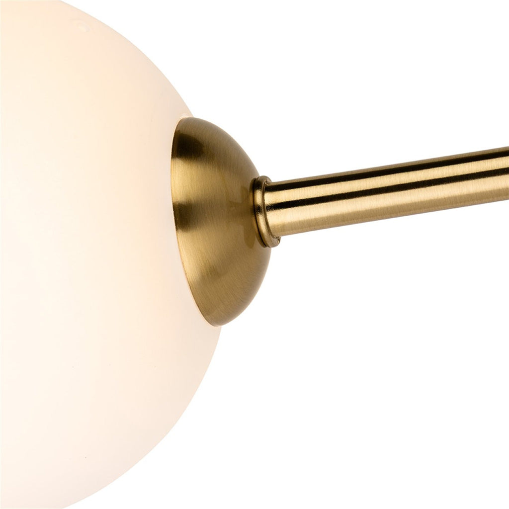 Close-up of an opal white glass shade on its brushed brass arm
