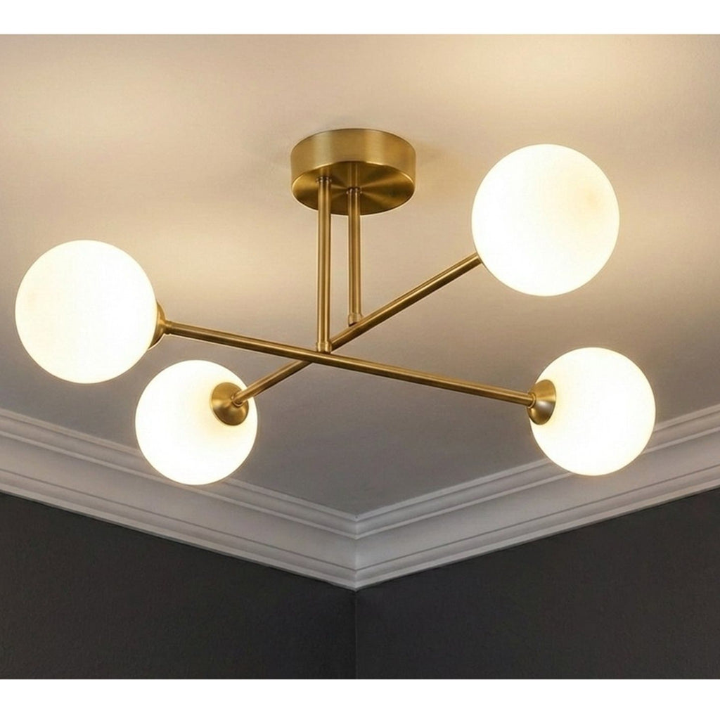Ripley Glass Globe 4 Light Semi-Flush Ceiling Light in brushed brass, lit on a bedroom ceiling