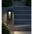 Selsey Oblong LED Wall & Step Light in graphite mounted on a garden wall beside outdoor steps at dusk