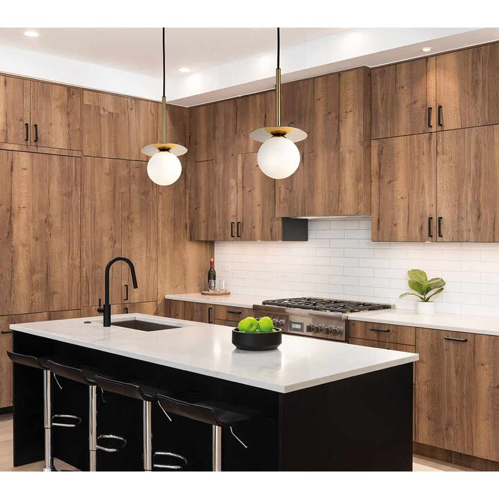 Two Thea Opal Globe Pendants in brushed brass hanging over a kitchen island